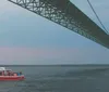 A tour boat named Ugly Anne is cruising near a large suspension bridge during a calm evening