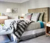 A well-appointed bedroom featuring a neatly made bed with a tufted headboard coordinating pillows a plush throw modern furniture and decorative accents creating a luxurious and cozy atmosphere