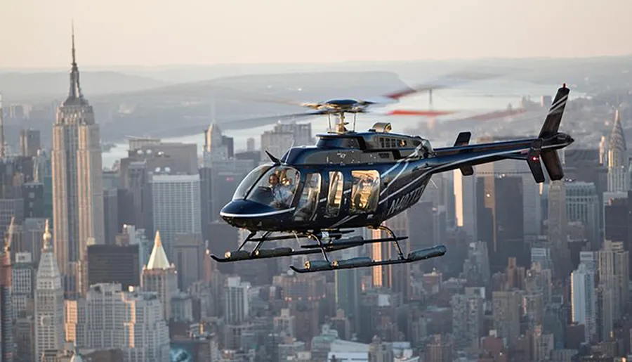 A helicopter flies over an urban landscape with skyscrapers during what appears to be dawn or dusk.