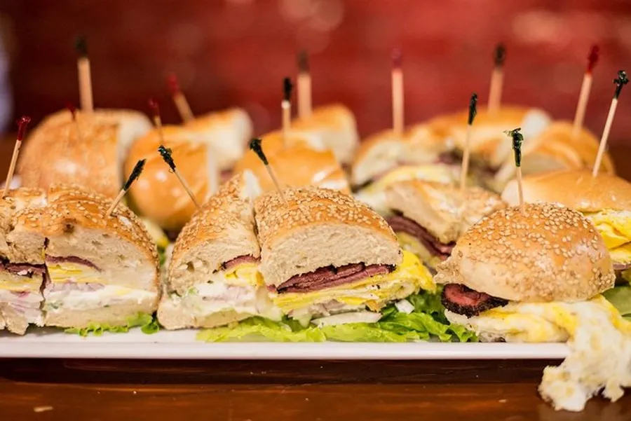 The image shows a platter of assorted cut sandwiches with toothpicks in them, ready to be served at a gathering.