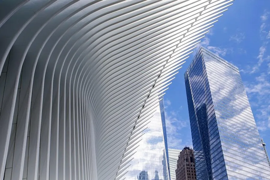 The image features the distinct, curved white ribs of the Oculus structure in lower Manhattan, contrasting with the surrounding skyscrapers under a blue sky.