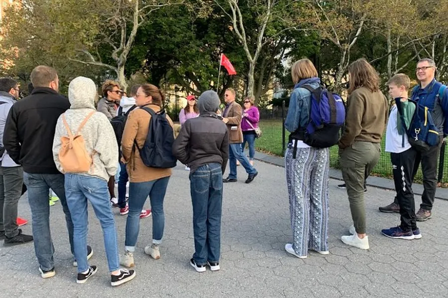 A group of people appear to be participating in an outdoor guided tour, with the guide holding a red flag for easy visibility.