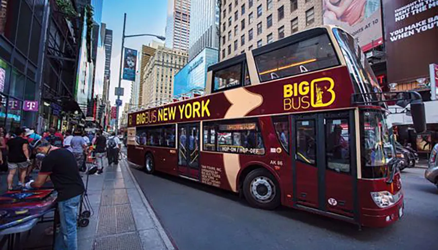 A red double-decker tour bus emblazoned with BIG BUS NEW YORK is driving through a bustling city street lined with people and illuminated signage.