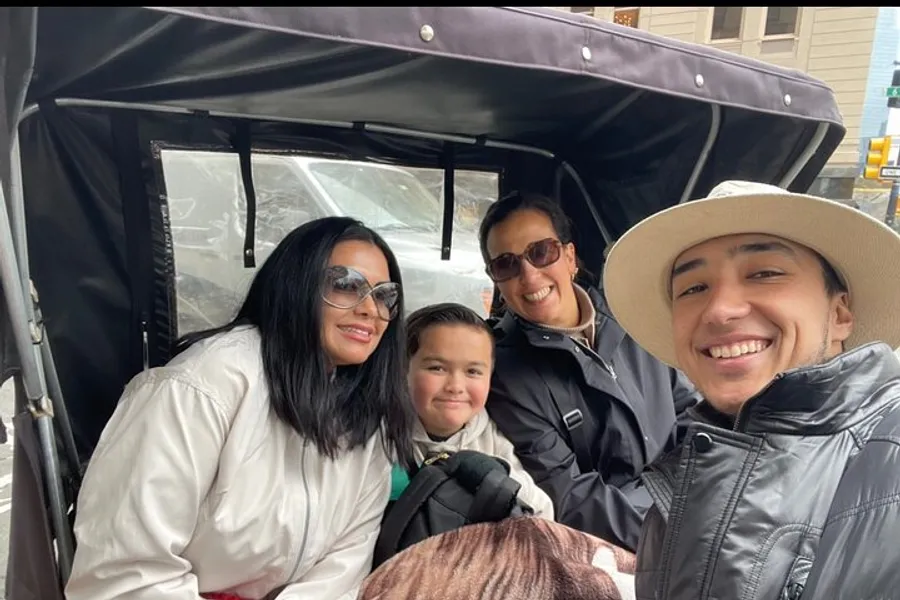 Four people are smiling for a selfie while seated in a horse-drawn carriage, creating a moment of shared happiness.