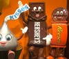 The image shows three anthropomorphic chocolate characters representing Hersheys Reeses and Hersheys Kisses smiling and posing together