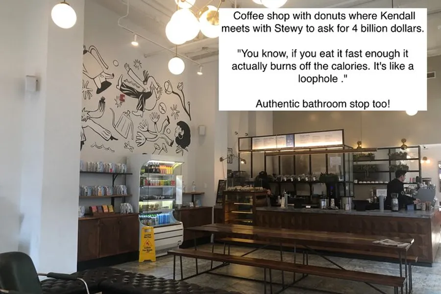 The image shows the interior of a coffee shop with a simple, modern decor and a whimsical wall art, accompanied by text overlays indicating a reference to a popular TV show scene and highlighting the authenticity of the location.