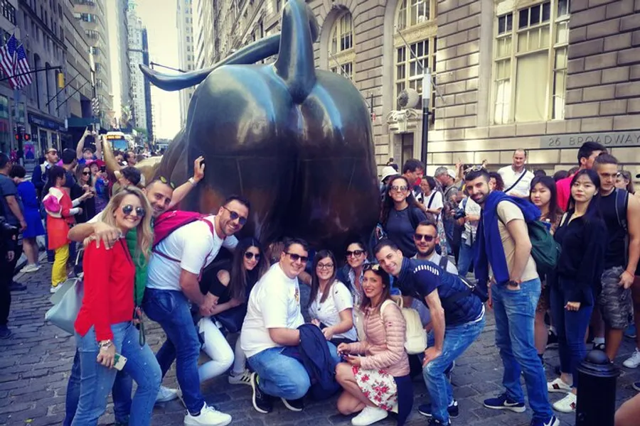 A group of people is posing for a photo with the Charging Bull sculpture in New York City.