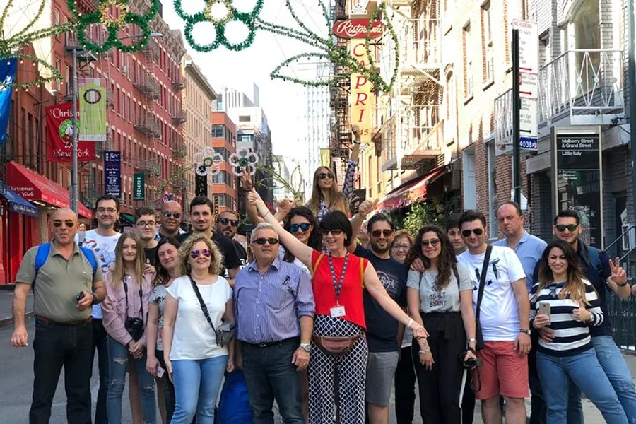 A diverse group of people is posing for a photo on a street adorned with festive decorations.