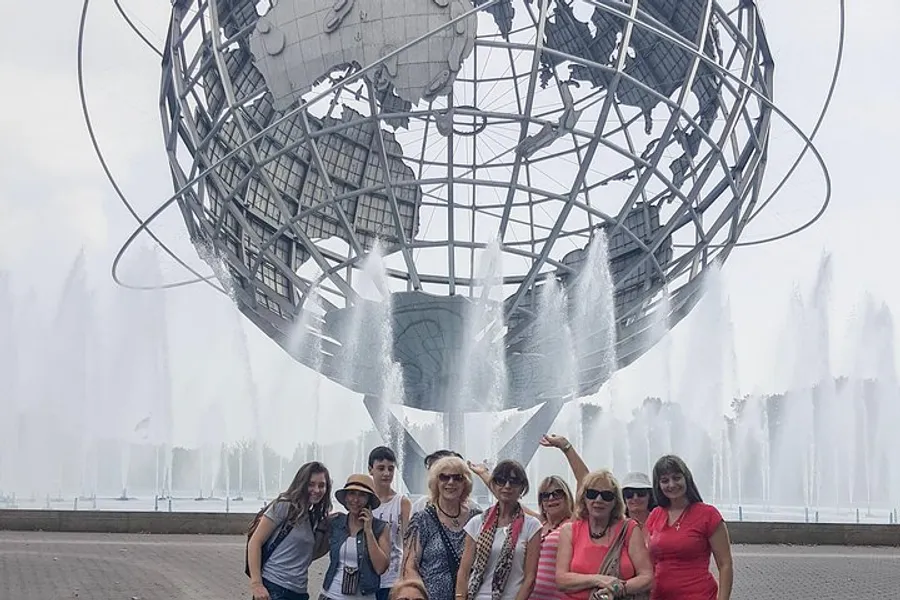 A group of people poses for a photo in front of the iconic Unisphere with fountains spraying water in the background.