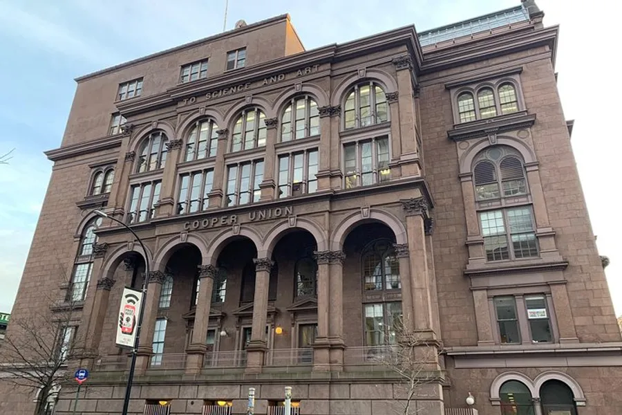 The image shows the exterior of the Cooper Union building, a historic brownstone facade with arched windows and an inscription stating To Science and Art.