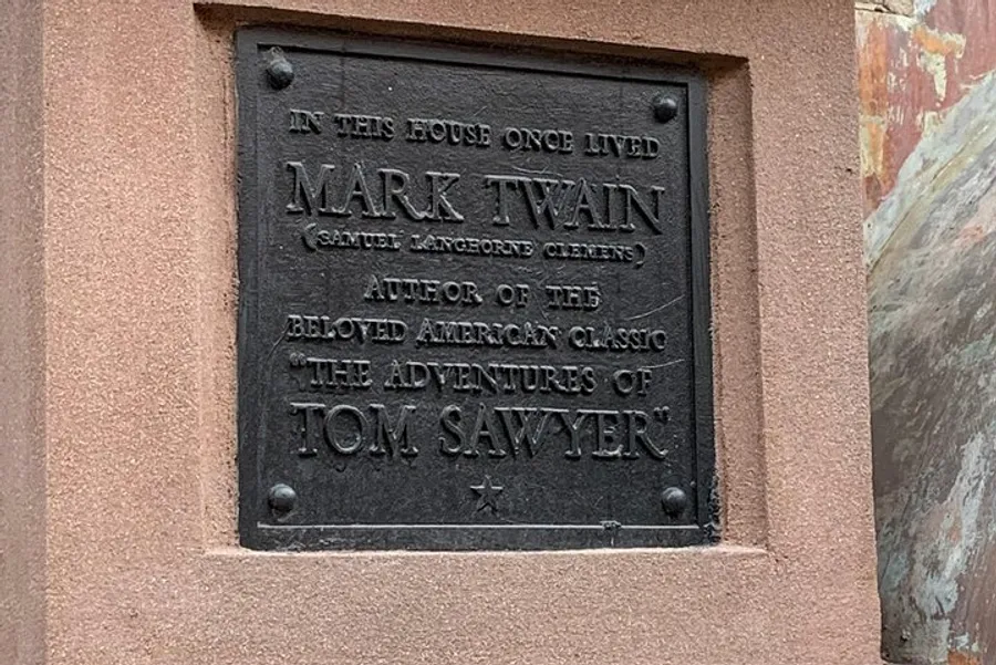 The image displays a commemorative plaque indicating that Mark Twain, author of The Adventures of Tom Sawyer, once lived in this house.