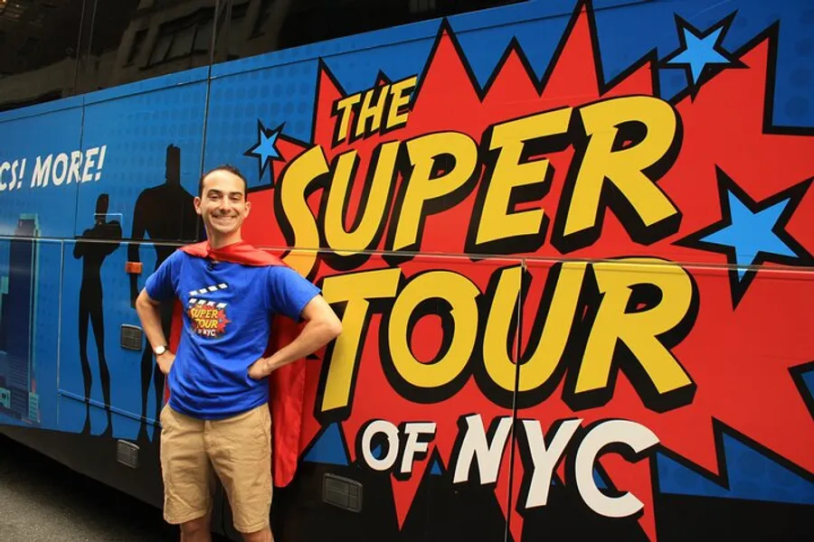 A cheerful person dressed in a superhero-style outfit with a cape is posing in front of a colorful bus advertising The Super Tour of NYC.