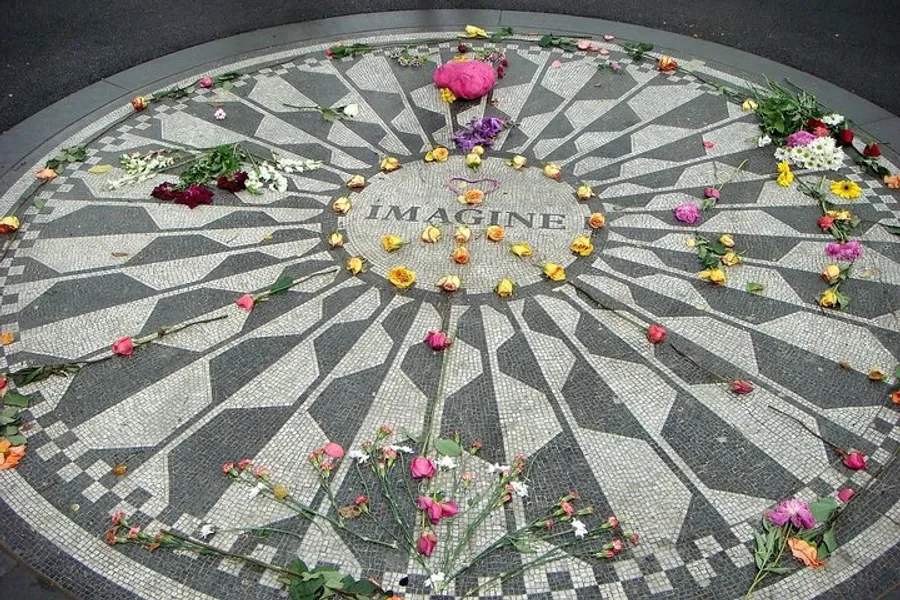 A mosaic with the word IMAGINE at the center is adorned with scattered flowers as a tribute.