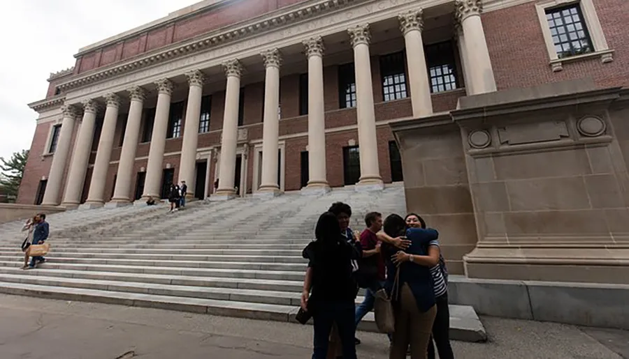 People are seen in front of a grand building with large columns and steps, engaging in various activities such as taking photos, walking, and having conversations.