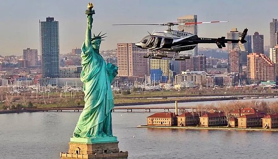 A helicopter is flying near the Statue of Liberty with a cityscape in the background.