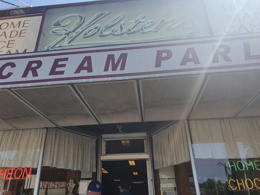 The image shows the entrance to Holsten's, an ice cream parlor with signage that includes words like Homemade Ice Cream and Home Made Chocolates, suggesting an establishment that offers desserts and sweets.