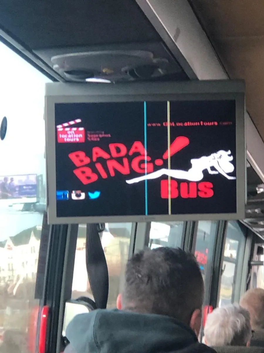The image shows a digital display inside a bus with the words BADA BING BUS in red letters, an outline of a bull, and blurry background that indicates it might be taken from a moving vehicle or in a crowded setting.