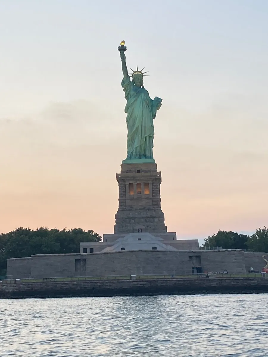 The Statue of Liberty stands tall against a dusky sky, symbolizing freedom and welcoming visitors at a waterfront location.