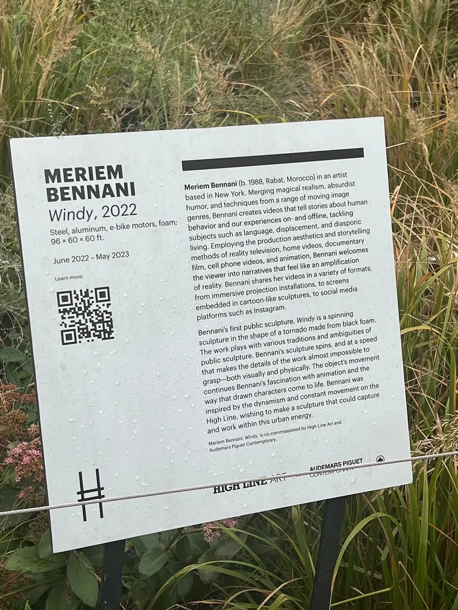 The image shows an information panel about an artwork titled Windy, 2022 by Meriem Bennani, mentioning the materials used and providing context about the artist and the work, with a QR code and logos of the sponsoring organizations at the bottom.