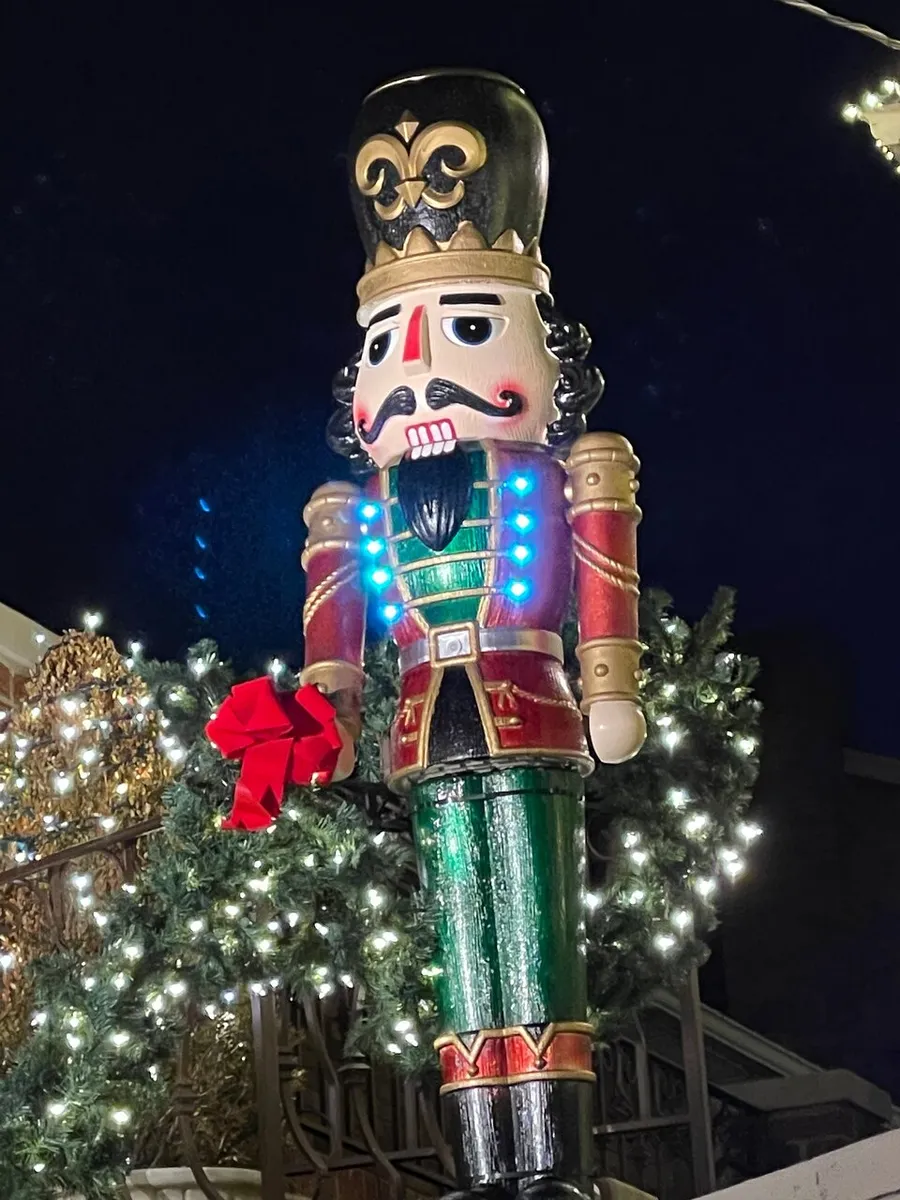 The image shows a large, illuminated nutcracker decoration surrounded by festive lights, likely part of a holiday display.