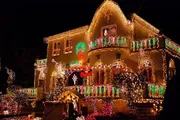 A house is extravagantly adorned with a vibrant display of Christmas lights, featuring wreaths, garlands, and festive decorations covering the entire façade.