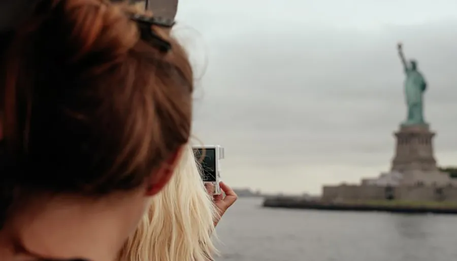 A person is taking a photo of the Statue of Liberty with their smartphone.