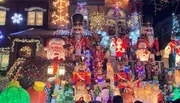 The image shows a house festively decorated with an abundance of Christmas lights and various holiday figures including Santa Claus, nutcrackers, and snowmen.
