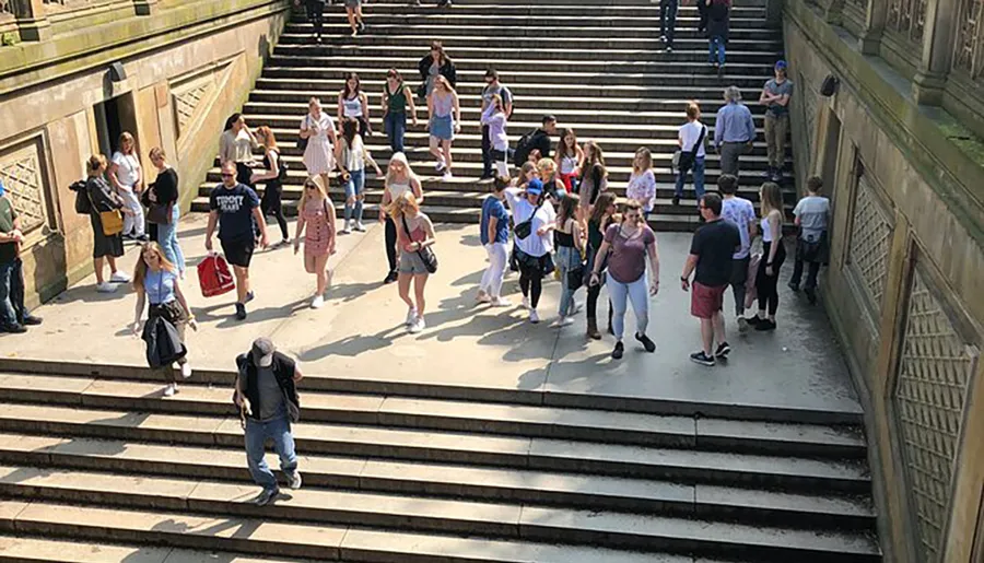 A group of people is seen ascending and descending a wide outdoor staircase on a sunny day.