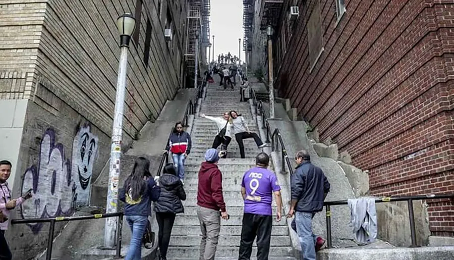 This photo captures multiple people on a steep urban staircase, some posing for pictures while others ascend or descend, amidst a casual atmosphere highlighted by graffiti on the wall.