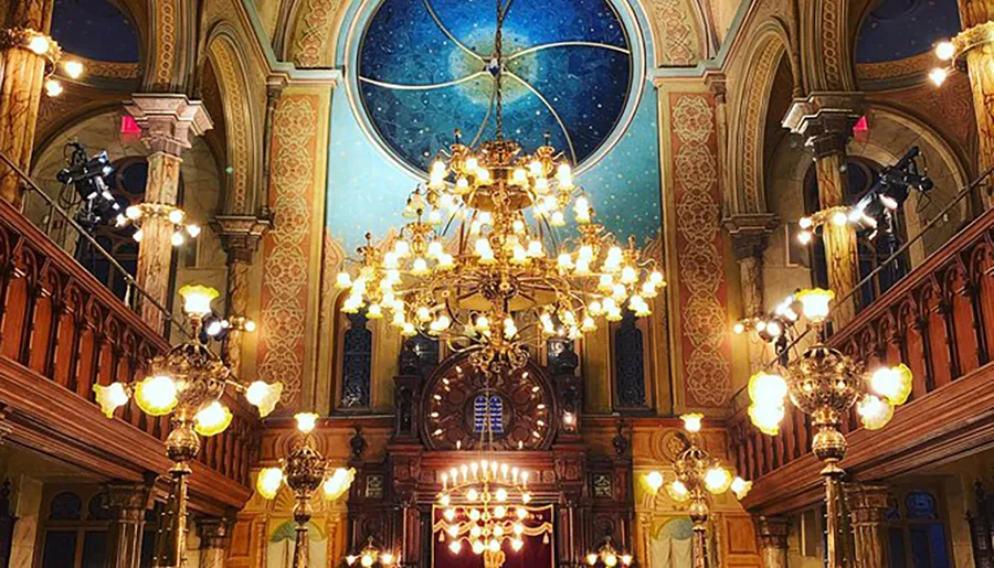 This image shows an ornate room with an elaborately decorated ceiling, multiple chandeliers, patterned walls, and an arched stained-glass window offering a luxurious and opulent interior.
