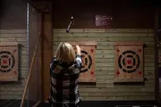 A person is throwing an axe toward a target at an indoor axe-throwing facility.