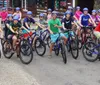 A group of young cyclists wearing helmets are posing for a photo with their mountain bikes