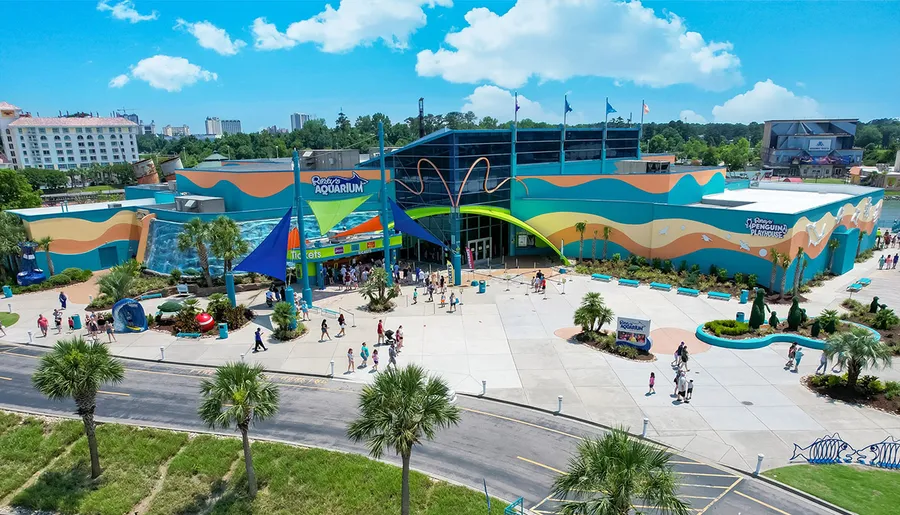 This is a vibrant aerial view of people visiting a colorful and lively aquarium on a sunny day.