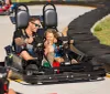 An adult and a child enjoy a thrilling go-kart ride together sharing a light-hearted moment full of smiles