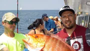 A man is holding a large, colorful fish aboard a boat with other people around, possibly after a successful fishing trip.