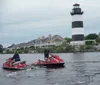Two people are riding a jet ski with water splashing around them as they speed across a lake