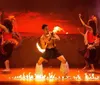 A performer with traditional tattoos is demonstrating a fire dance at night skillfully manipulating flaming objects