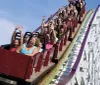 Thrilled passengers raise their hands as they experience the exciting descent on a wooden roller coaster