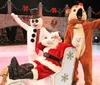 Santa Claus is lounging in a chair on an ice rink while a person in a snowman costume and another in a reindeer costume pose playfully beside him in a festive holiday setting
