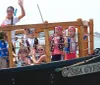 A group of people enjoy a boat ride on a miniature pirate ship flying a Jolly Roger flag
