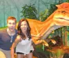 Three people appear to be playfully interacting with a Tyrannosaurus rex in a staged jungle setting