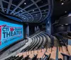 The image shows an empty modern theater with a large screen displaying CTI 3D Giant Theater from the Pink Palace Family of Museums featuring stadium-style seating and an architectural ceiling design