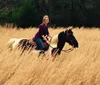 A person is smiling while riding a horse through a field of tall golden grass