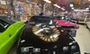 A black 1979 Pontiac Trans Am with a golden bird decal is displayed in a car museum, surrounded by other vintage vehicles and automotive memorabilia on the walls.