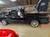 A black pickup truck is displayed inside a wooden garage with various automotive parts on the walls.