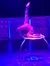 A contortionist is performing an impressive pose on a circular platform, with vibrant purple lighting illuminating the scene.