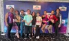 A group of people, including performers and attendees, pose together in front of a 