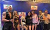 A group of people, including two casually dressed individuals and performers in elaborate costumes, pose in front of a 