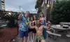 A group of people wearing festive attire are posing for a photo with a man in tropical-themed costume, exuding a cheerful and playful atmosphere.