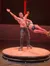 A man in leather roller skates performs a stunt with a woman on a wooden platform in a theatrical setting.